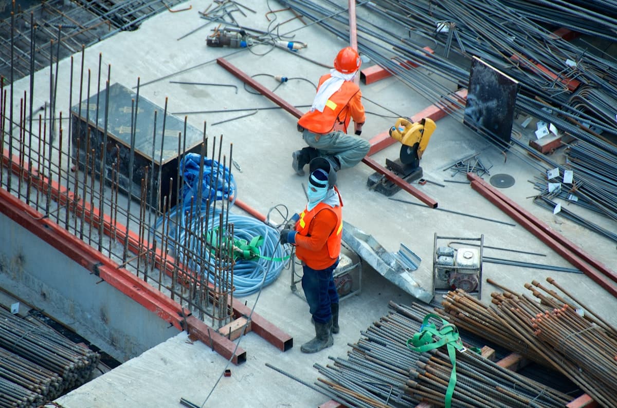 Construction workers on a job site with steel rebar and building materials
