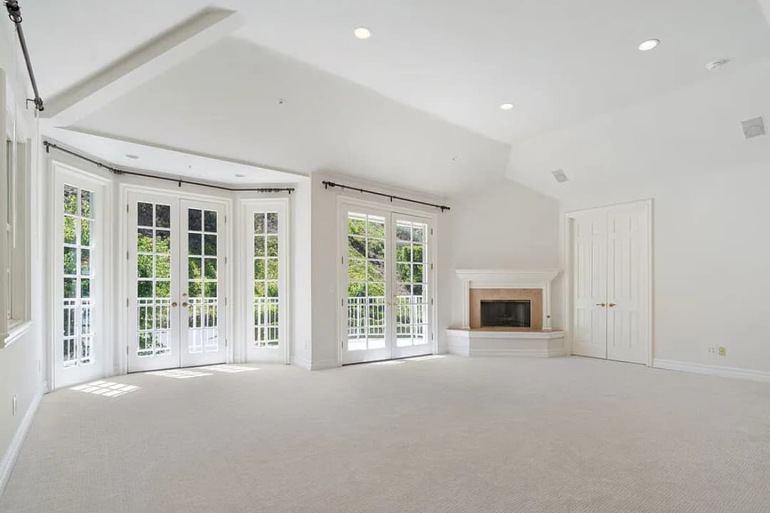 Bienveneda Estate primary suite with French doors, balcony access, and fireplace